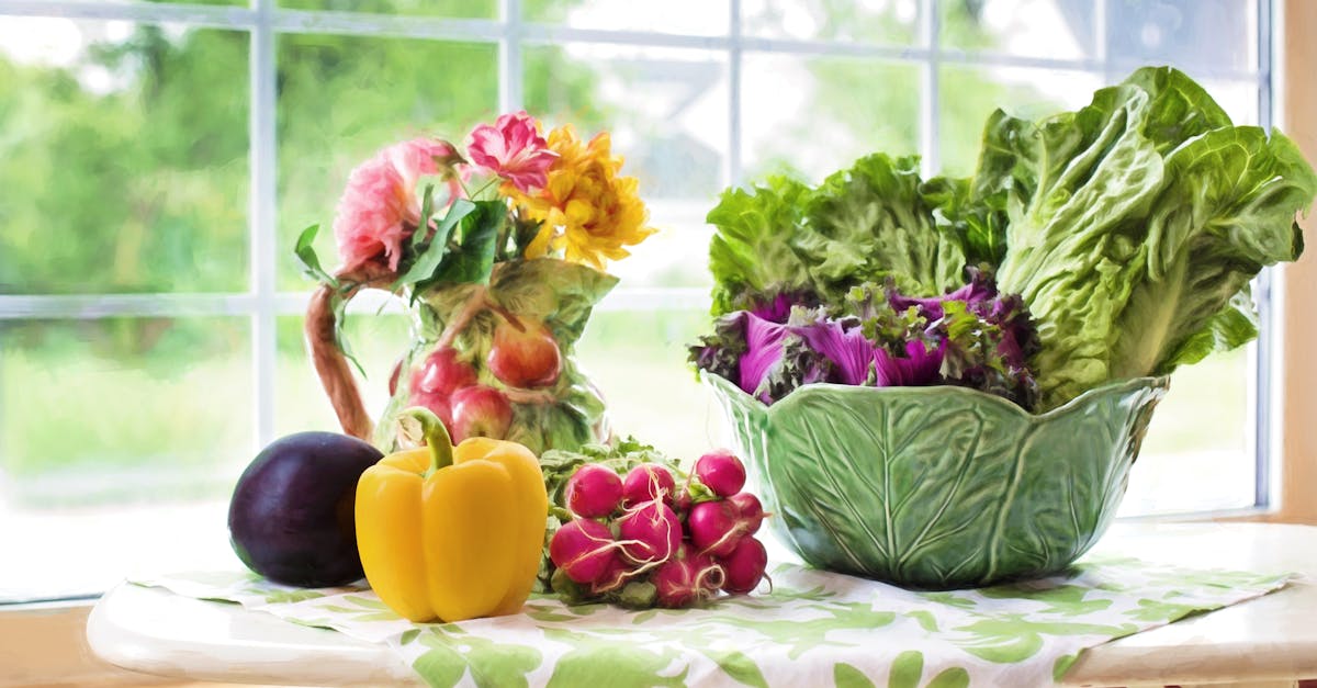 A vibrant display of fresh vegetables and flowers on a sunlit kitchen table by the window.